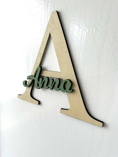 Einzigartige Namensschilder für die Zimmertüre aus MDF, zweifarbig lackiert. Das Türschild besteht aus einem 20 cm großen Buchstaben A und dem ausgeschriebenen Namen Anna, fixiert auf dem Großbuchstaben. Befestigt an einer weißen Türe.