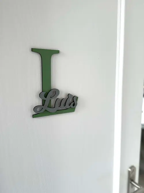 Einzigartige Namensschilder für die Zimmertüre aus MDF, zweifarbig lackiert. Das Türschild besteht aus einem 20 cm großen Buchstaben L und dem ausgeschriebenen Namen Luis, fixiert auf dem Großbuchstaben. Befestigt an einer weißen Türe.
