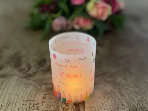 Lichthüllen Einschulung aus transparentem Papier, für Mädchen, bedruckt mit Farbstiften, Meine Einschulung, dem Namen und dem Datum der Einschulung. Dekoriert auf einem Holztisch mit einem entzündetem Teelicht