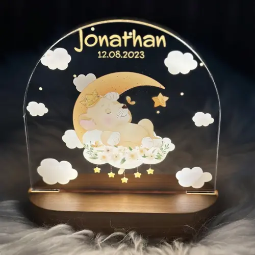 LED Nachtlicht für Kinder, ovaler, massiver Holzsockel mit Touchscreen, Acrylscheibe bedruckt mit auf einem Mond lliegenden Löwenbaby-Motiv in Aquarelloptik.