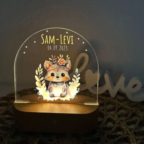 LED Nachtlicht für Kinder, ovaler, massiver Holzsockel mit Touchscreen, Acrylscheibe bedruckt mit Tierbaby-Motiven in Aquarelloptik. Abgebildet ist ein kleiner Waschbär mit Blumengebinde auf dem Kopf