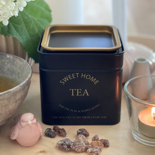 Mattchwarze, quadratische Teedose, mit goldenem Rand am Deckel, personalisiert mit goldenem Aufdruck "SWEET HOME TEA"