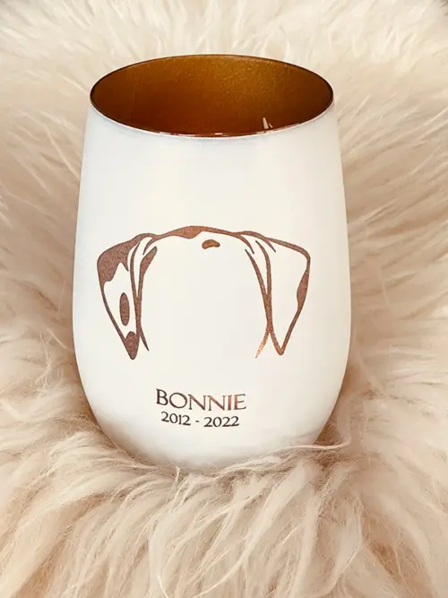 Windlicht Hund, Glas innen gold, Außen weiss, mit graviertem Hundemotiv, Namen des Hundes, Geburtsjahr und Sterbejahr, dekoriert auf einem weißen Fell