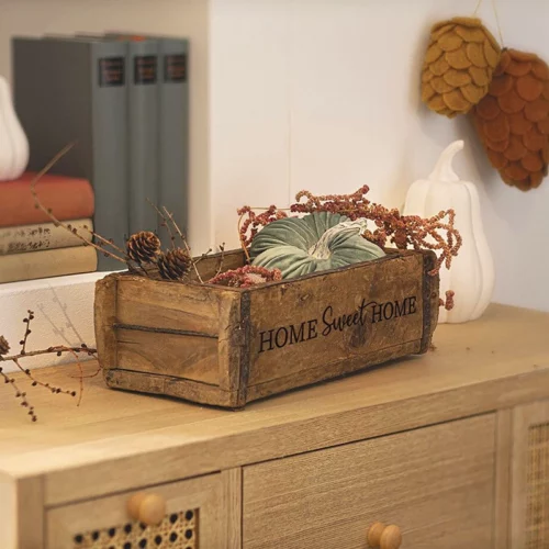 Alte Ziegelform als Aufbewahrungskiste, personalisiert mit dem Schriftzug Home Sweet Home, stehend auf einem Holzschränkchen, dekoriert mit herbstlichen Pflanzen